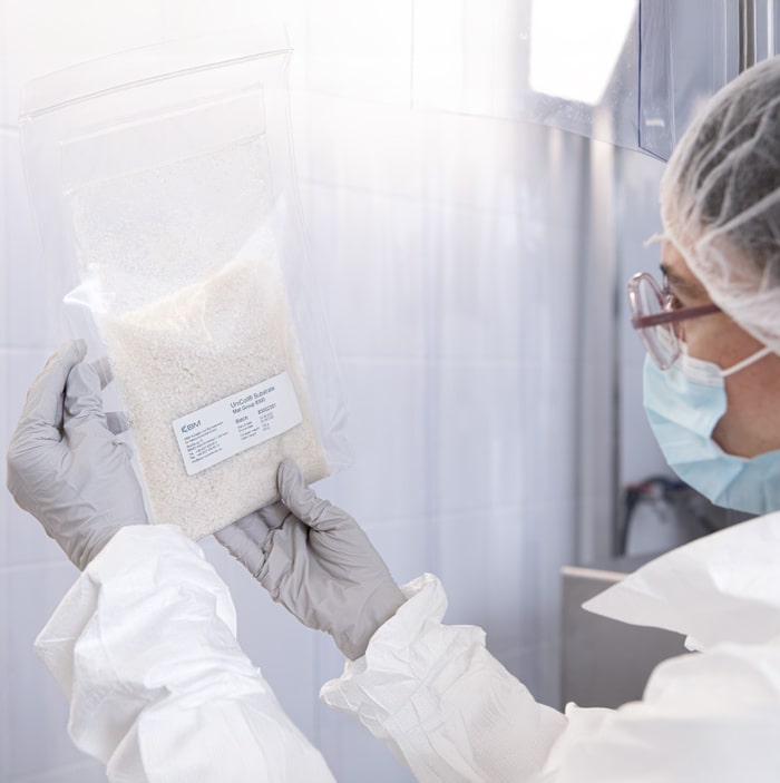 A laboratory technician holds packaging labelled UniColl® under cleanroom conditions.